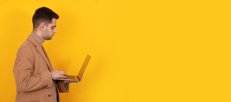 young man with beard coat and computer isolated on backgroundの写真素材