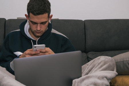 young man with computer, mobile phone and headphones at homeの写真素材