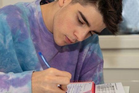 male teenager studying and writing