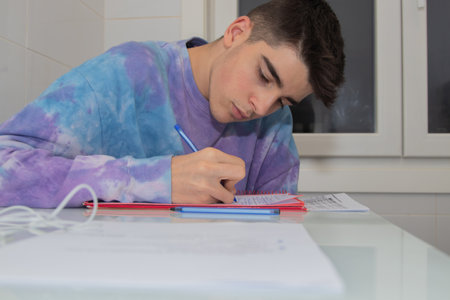male teenager studying and writing