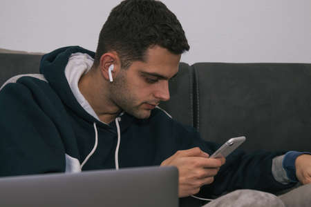 young man with computer, mobile phone and headphones at home