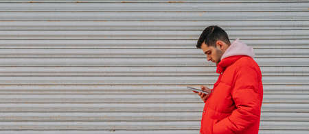 casual young man with mobile phone on urban street outdoors