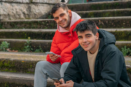 young people having fun with mobile phones on the stairs of the city streetの写真素材