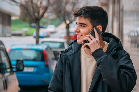 young teenager or student talking on mobile phone on the streetの写真素材