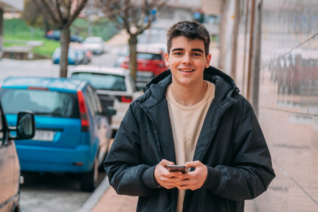 smiling teenager or student with mobile phone on the streetの写真素材