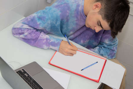 young teenager studying or writing at the desk