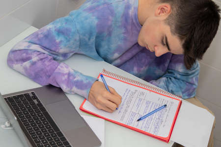 young teenager studying or writing at the desk