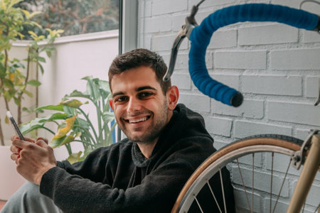young man at home with mobile phone sitting on the floorの写真素材