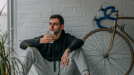 young man sitting at home with mobile phoneの写真素材