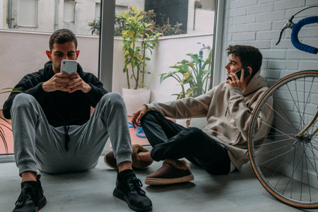 young people at home with mobile phones sitting on the floorの写真素材