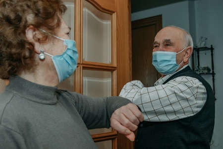 grandparents or seniors saluting each other with a mask in the coronavirus pandemicの写真素材