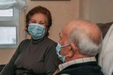 elderly couple or grandparents talking or meeting with maskの写真素材