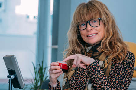 influencer at home showing cosmetics online with mobile phoneの写真素材