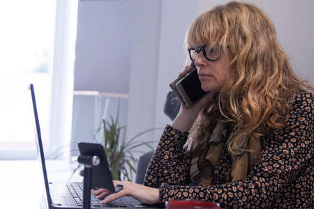 woman at home with mobile phone on the sofaの写真素材
