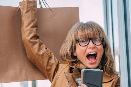 excited woman with shopping bags and mobile phoneの写真素材