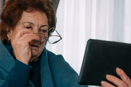 grandmother or elderly woman with tablet talking onlineの写真素材