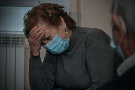 senior woman with mask with symptoms of illness or painの写真素材