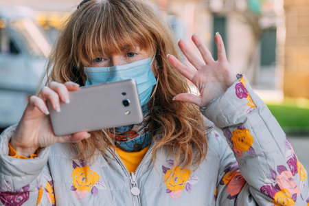 woman with mask talking on mobile phone on video callの写真素材