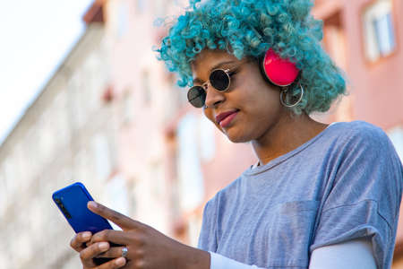 afro american girl smiling with headphones and mobile phone in the city