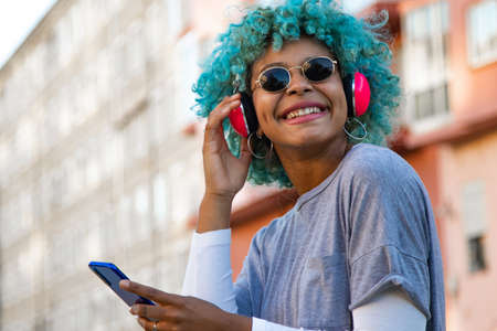 afro american girl smiling with headphones and mobile phone in the cityの写真素材