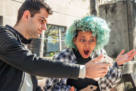 couple looking at mobile phone checking with surpriseの写真素材