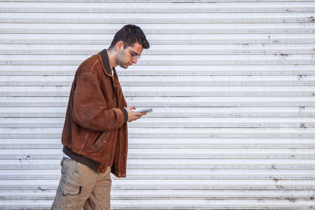 young man walking on the street looking at mobile phone