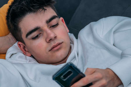 young man with phone on the sofaの写真素材