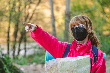 woman with mask and map hikingの写真素材