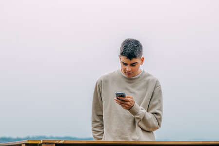 young teenager using mobile phone outdoorsの写真素材