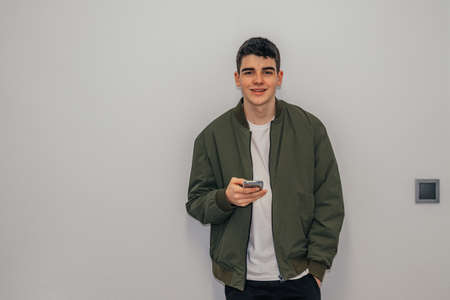 teenager boy with mobile phone at home wall isolated