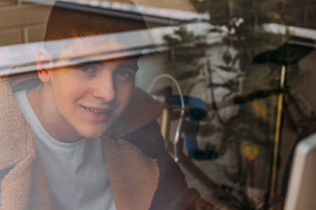 portrait of male teenager behind window pane