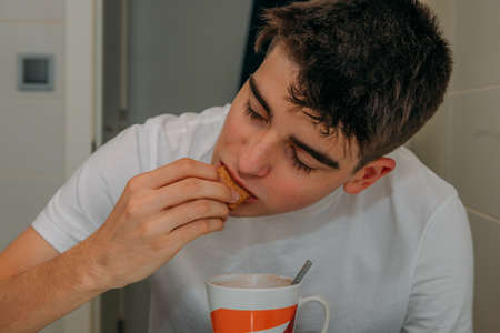 young man having breakfast in the kitchen at homeの写真素材