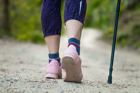 feet on dirt road with trekking pole