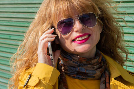 portrait of adult woman with mobile phone and sunglassesの写真素材