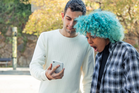 young man showing mobile phone to surprised girlの写真素材