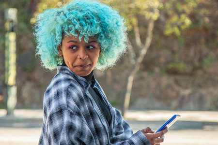 portrait of afro american girl with mobile phone looking sideways
