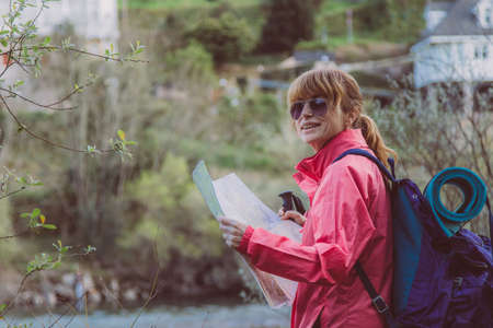 woman with hiking map with backpack in nature