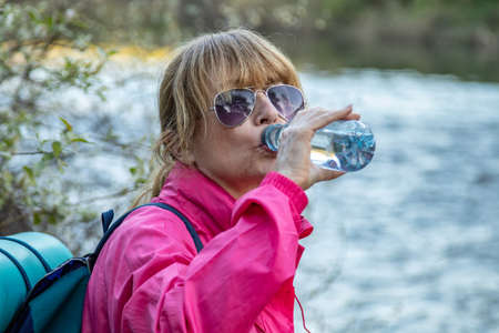 travel or hiking woman with backpack drinking water