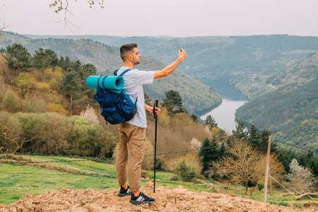 young man hiking or hiking taking pictures with mobile phoneの写真素材