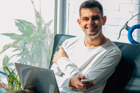 young man at home with phone and computer