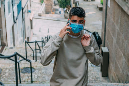 young man in mask shopping with mobile phone on the streetの写真素材