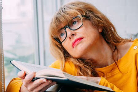 woman at home with book in the window