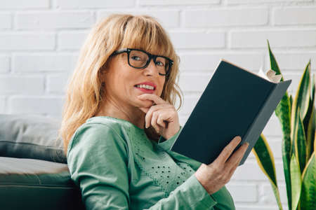 adult woman reading a textbook at home
