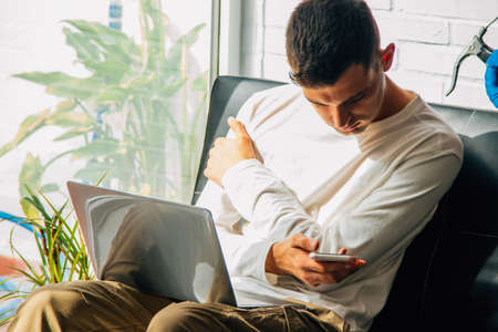 man at home with computer and mobile phoneの写真素材