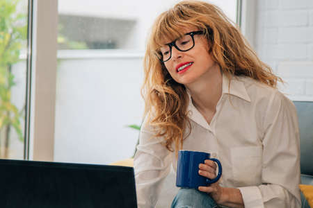 woman at home with computer and cup of coffee