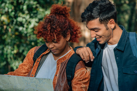 young people traveling looking at the map outdoors with backpacksの写真素材