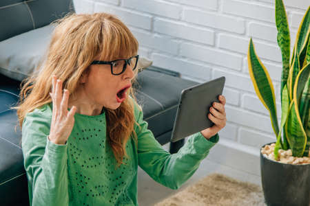 woman at home looking surprised at the digital tablet