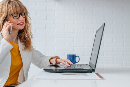 business woman with mobile phone and computer in officeの写真素材