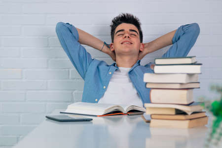relaxed student at the desk with stacked books