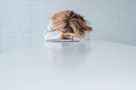 defeated or tired businesswoman on top of the tableの写真素材